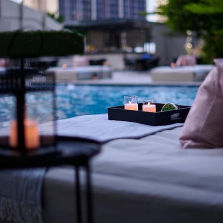 Отель Jw Marriott Куала-Лумпур Экстерьер фото The photo depicts a serene setting by a pool. In the foreground, there is a table with a lantern and candles, creating a cozy atmosphere. A tray on a lounge area holds three glasses and some greenery. Soft pillows add comfort, and the pool reflects t