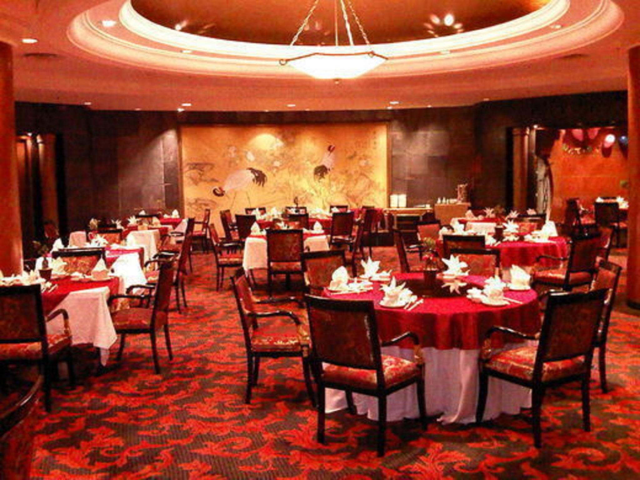 Отель Jw Marriott Куала-Лумпур Экстерьер фото The photo shows an elegantly styled restaurant interior. There are several dining tables arranged in the space, each set with white tablecloths and decorative tableware, including folded napkins. The floor is covered with a patterned red carpet, whic