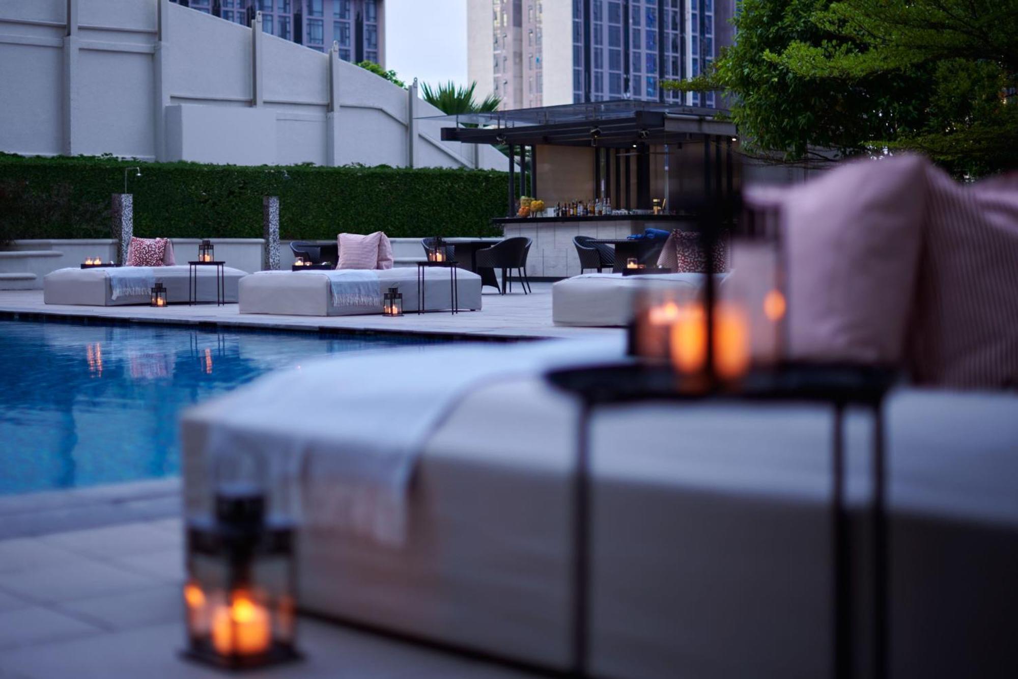Отель Jw Marriott Куала-Лумпур Экстерьер фото The photo depicts a serene outdoor pool area, featuring lounge seating arranged near the water. There are several cushioned lounges with soft pillows, as well as decorative lanterns placed on small tables, providing a warm, inviting ambiance. In the 