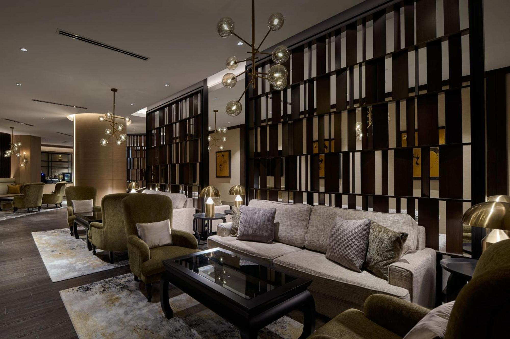 Отель Jw Marriott Куала-Лумпур Экстерьер фото The photo depicts a modern and stylish lounge or living area. It features elegant furnishings, including plush sofas and armchairs in muted colors, arranged around a dark coffee table. The walls have a stylish wooden paneling design that adds a sophi