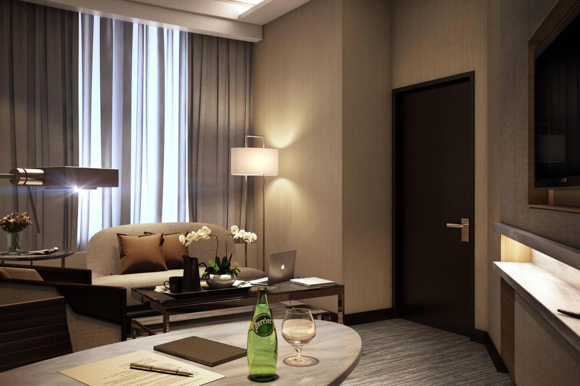 Отель Jw Marriott Куала-Лумпур Экстерьер фото The photo depicts a stylish hotel room or modern living space. There is a comfortable sofa with decorative pillows, situated beside a floor lamp. A small table is placed nearby, featuring a green bottle of water, a glass, and some stationery items li