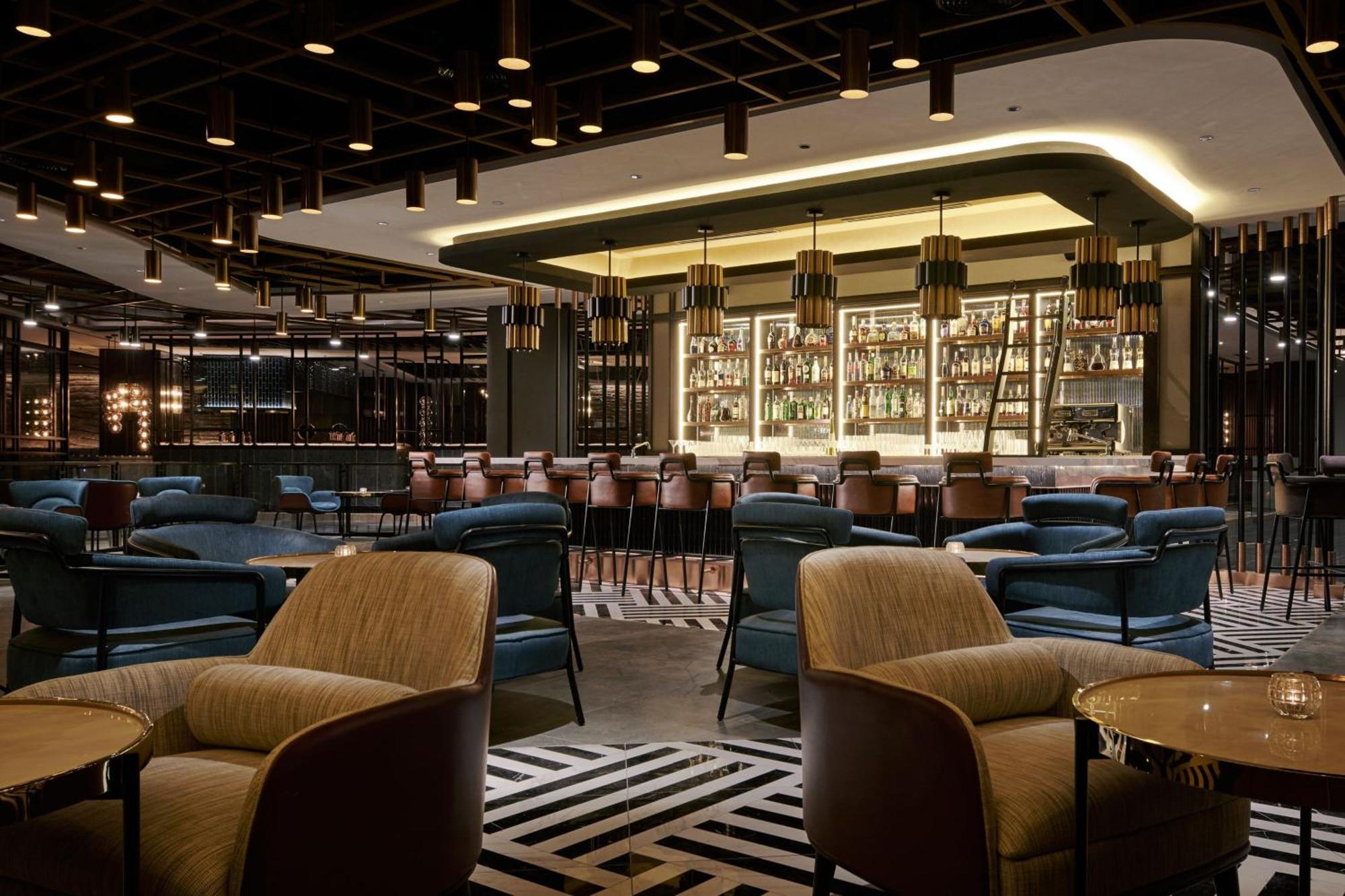 Отель Jw Marriott Куала-Лумпур Экстерьер фото The photo depicts an elegant bar or lounge area inside a modern restaurant. The space features a stylish design with a combination of seating options, including plush armchairs and bar stools. The bar is well-stocked with a variety of bottles display