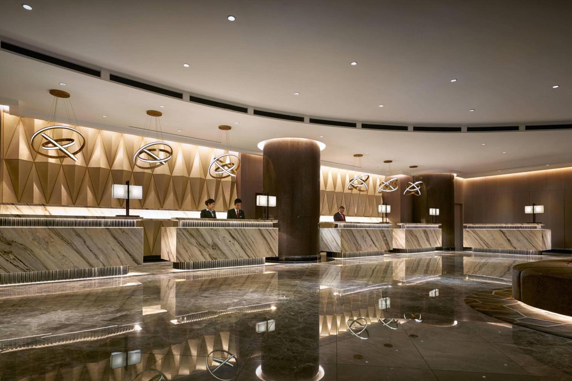 Отель Jw Marriott Куала-Лумпур Экстерьер фото The photo depicts a modern hotel lobby with a sleek and elegant design. The reception area features a long, polished marble counter that reflects the ambient lighting. Behind the counter, there are several staff members, indicating that the space is 